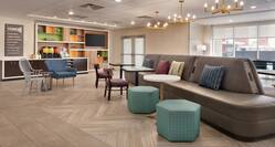Bright lobby featuring comfortable seating area, self serve coffee station, and TV.
