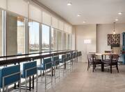 Bright lobby area featuring floor to ceiling windows, bar stool seating, and business area.