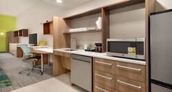 Spacious accessible studio suite featuring fully equipped kitchen, work desk with ergonomic chair, and TV.