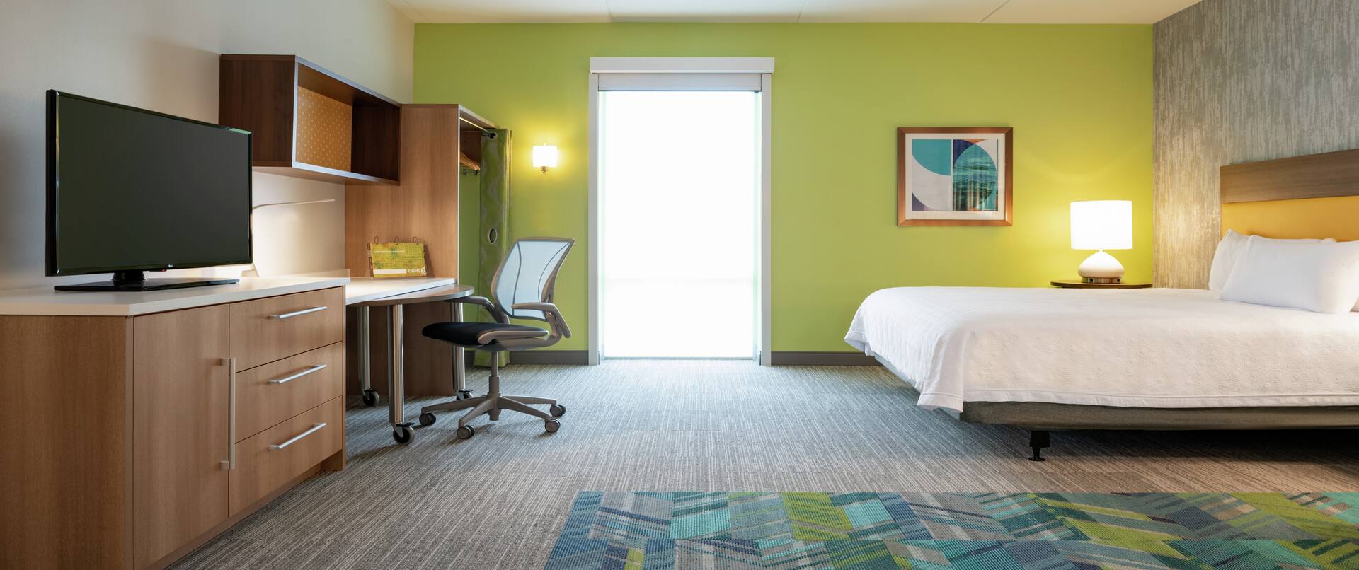 Spacious accessible suite featuring TV, work desk with ergonomic chair, and comfortable king bed.
