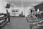 Spacious fitness center featuring cardio machines, free weights, TV, and complimentary towels.