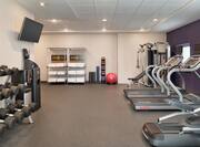 Spacious fitness center featuring cardio machines, free weights, TV, and complimentary towels.