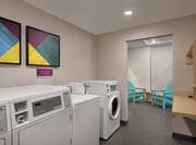Convenient on-site coin operated guest laundry machines with folding table and seating area.