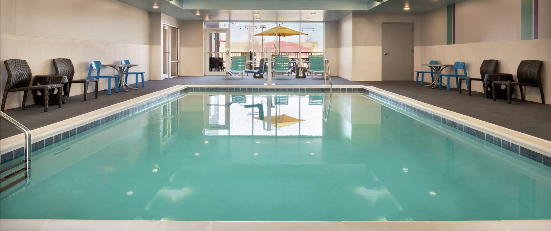 Spacious indoor pool featuring lounge chairs, accessible chair lift, and floor to ceiling window.