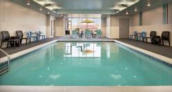 Spacious indoor pool featuring lounge chairs, accessible chair lift, and floor to ceiling window.