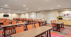 Spacious meeting room featuring classroom style tables and chairs, coffee break area, and TV.