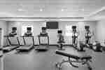 Ampio fitness center con macchine cardio, fontana d'acqua, panca da allenamento e pesi liberi.