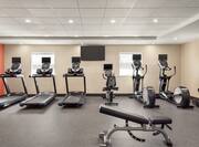 Spacious fitness center featuring cardio machines, water fountain, workout bench, and free weights.