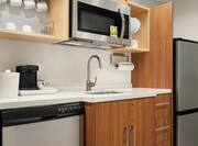 Fully equipped studio kitchen featuring dishwasher, fridge, microwave, and coffee maker.