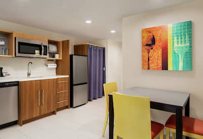 Spacious kitchen in suite featuring eat-in dining table, dishwasher, fridge, microwave, and coffee maker.