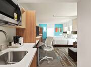 Spacious studio suite featuring fully equipped kitchen, work desk with ergonomic chair, TV, and two queen beds.