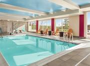Bright indoor pool featuring floor to ceiling windows, ample seating, and accessible chair lift.