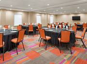 Spacious meeting room featuring wedding setup with round tables, glasses, plates, and flatware.