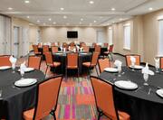 Spacious meeting room featuring wedding setup with round tables, glasses, plates, and flatware.