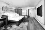 Camera moderna con letto king size, scrivania, TV, armadio e pareti decorative.