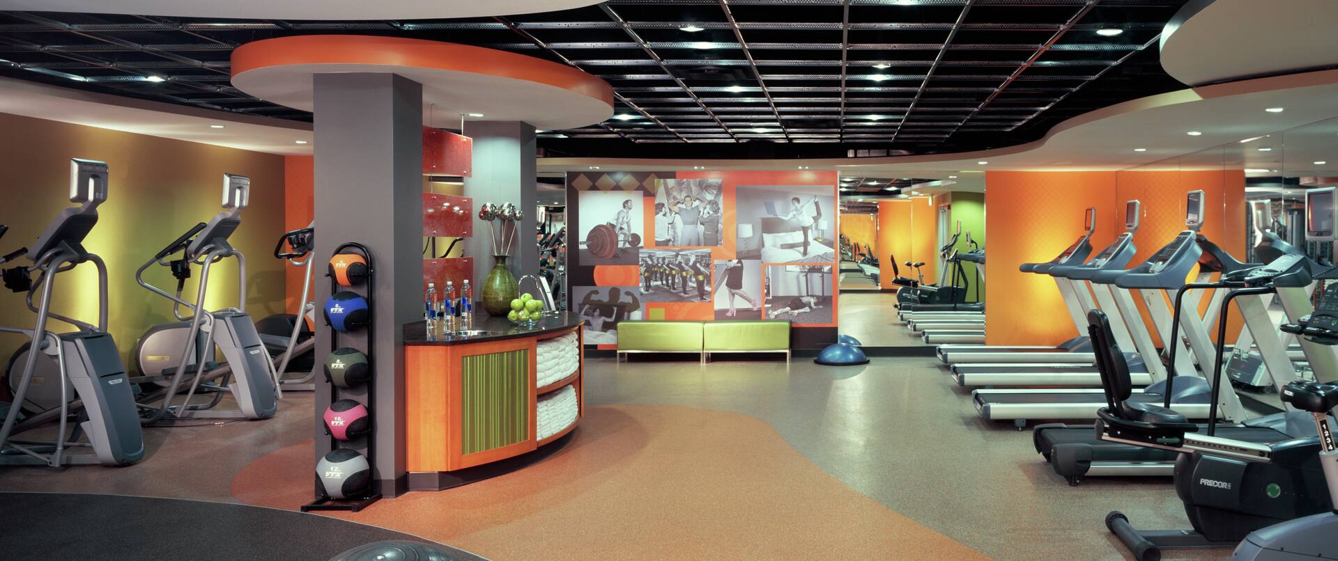 a fitness center with exercise machines and a counter with water and towels