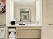 Spacious accessible bathroom featuring large vanity, mirror, and grab bars for guest safety.