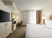 Bright studio suite featuring comfortable king bed, work desk, and TV.