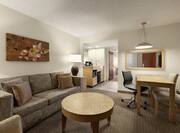 Spacious living area in suite featuring comfortable sofa, dining table, wet bar, and private bedroom.