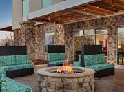 Comfortable outdoor lounge area with sofa style seating, string lights, and firepit.