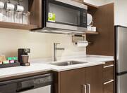 Fully equipped kitchen in studio suite featuring fridge, dishwasher, microwave, and coffee maker.