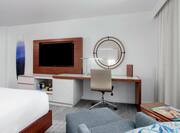 a bed, lounge chair, desk and tv in a guest room