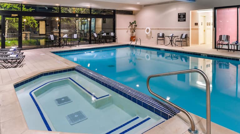 Whirlpool and Heated Indoor Swimming Pool Surrounded by Lounge Chairs and Windows With Outside Views