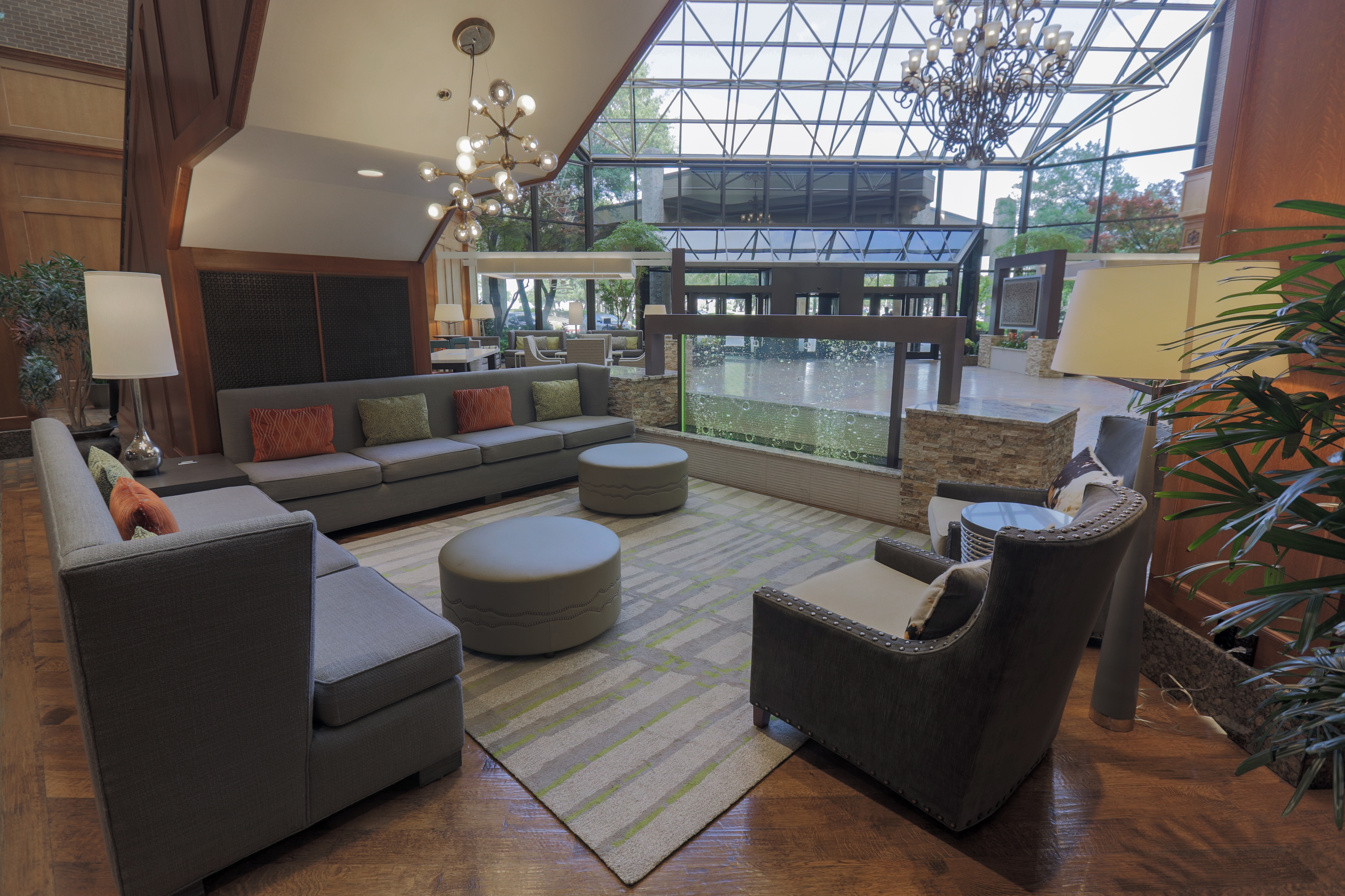 Lobby Seating Area with Couches and Footstools Next to a Floor to Ceiling Window Looking Over Hotel Entrance