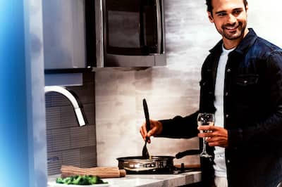 Smiling man holding drink while cooking