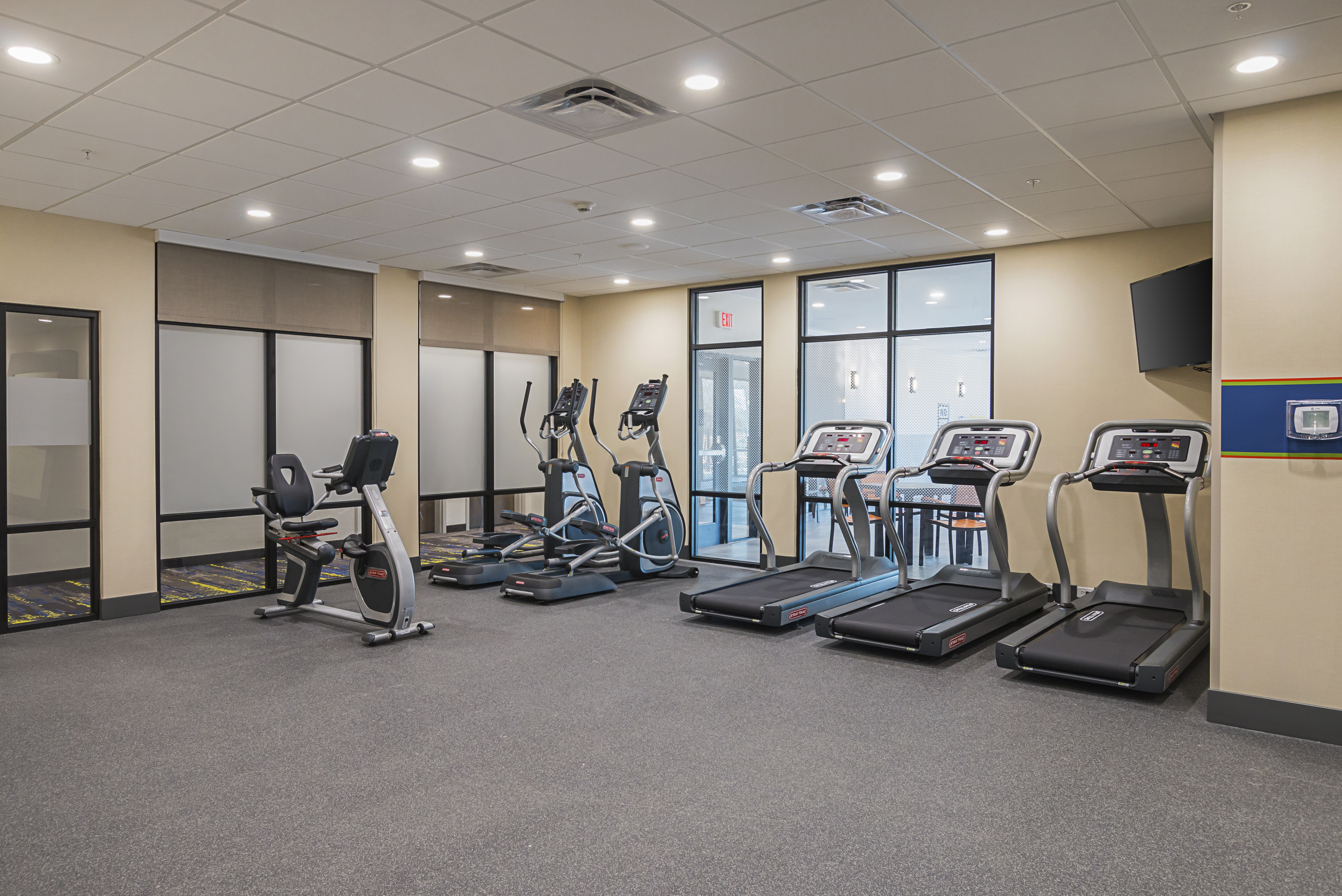 Large fitness center with three
  treadmills on right with recumbant bike on left and elliptical machines in
  the middle 