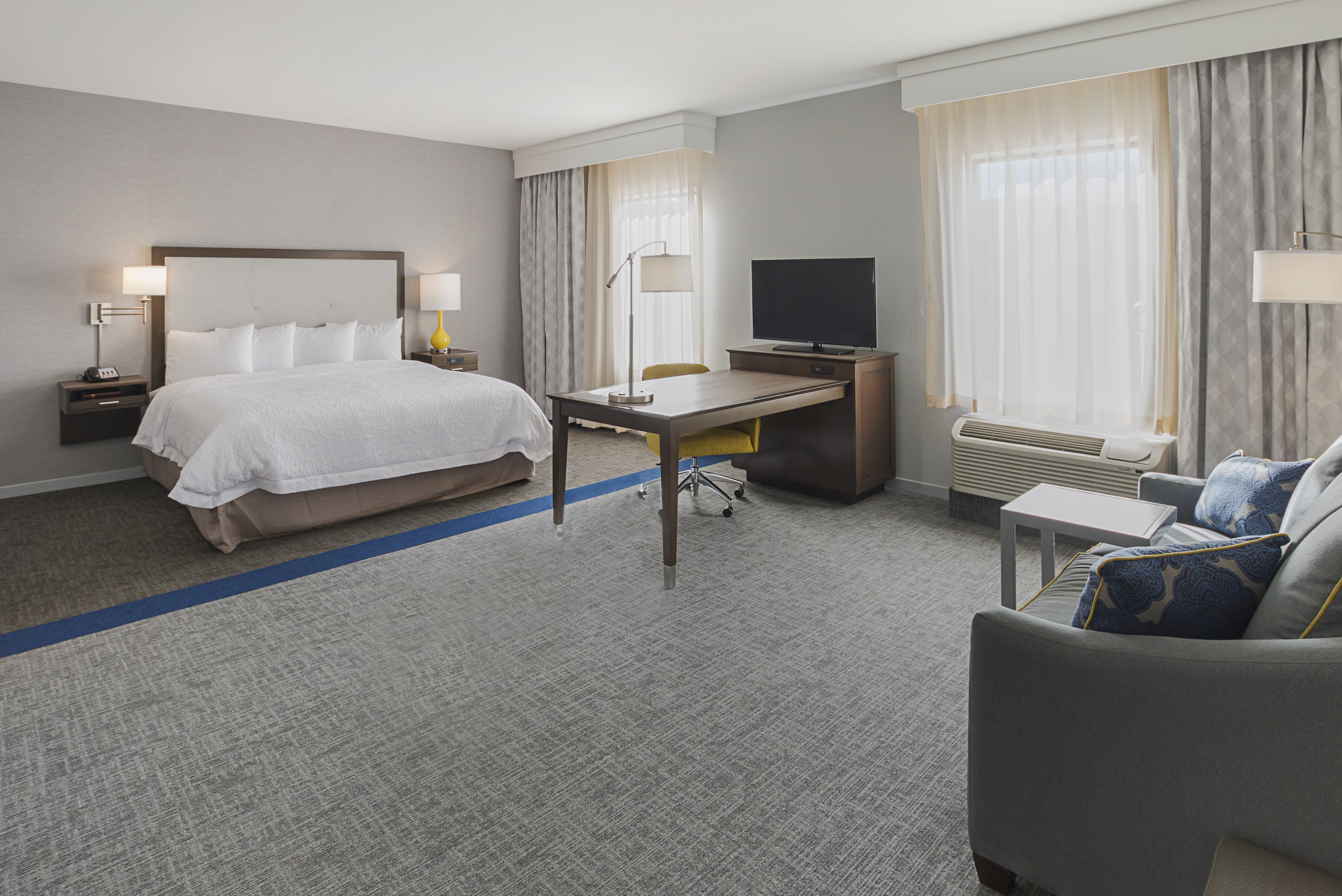 Hampton Inn studio room with king bed,
  desk, desk chair, sofa bed, and seating area