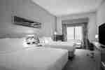 Two guest beds with nightstand between them and a work desk in guest room