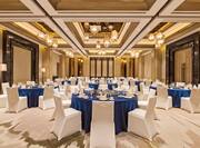 Ballroom dining tables and chairs covered in cloth with dining amenities