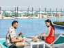 Man and woman relaxing by pool with food and drink