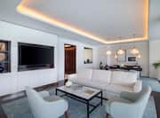 Lounge area with sofa, chairs, dining table and wall mounted TV