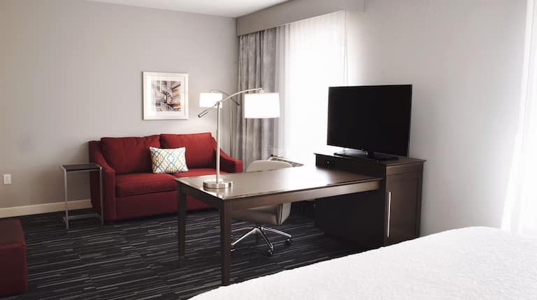 Suite with king bed, sofa bed, work desk, and TV