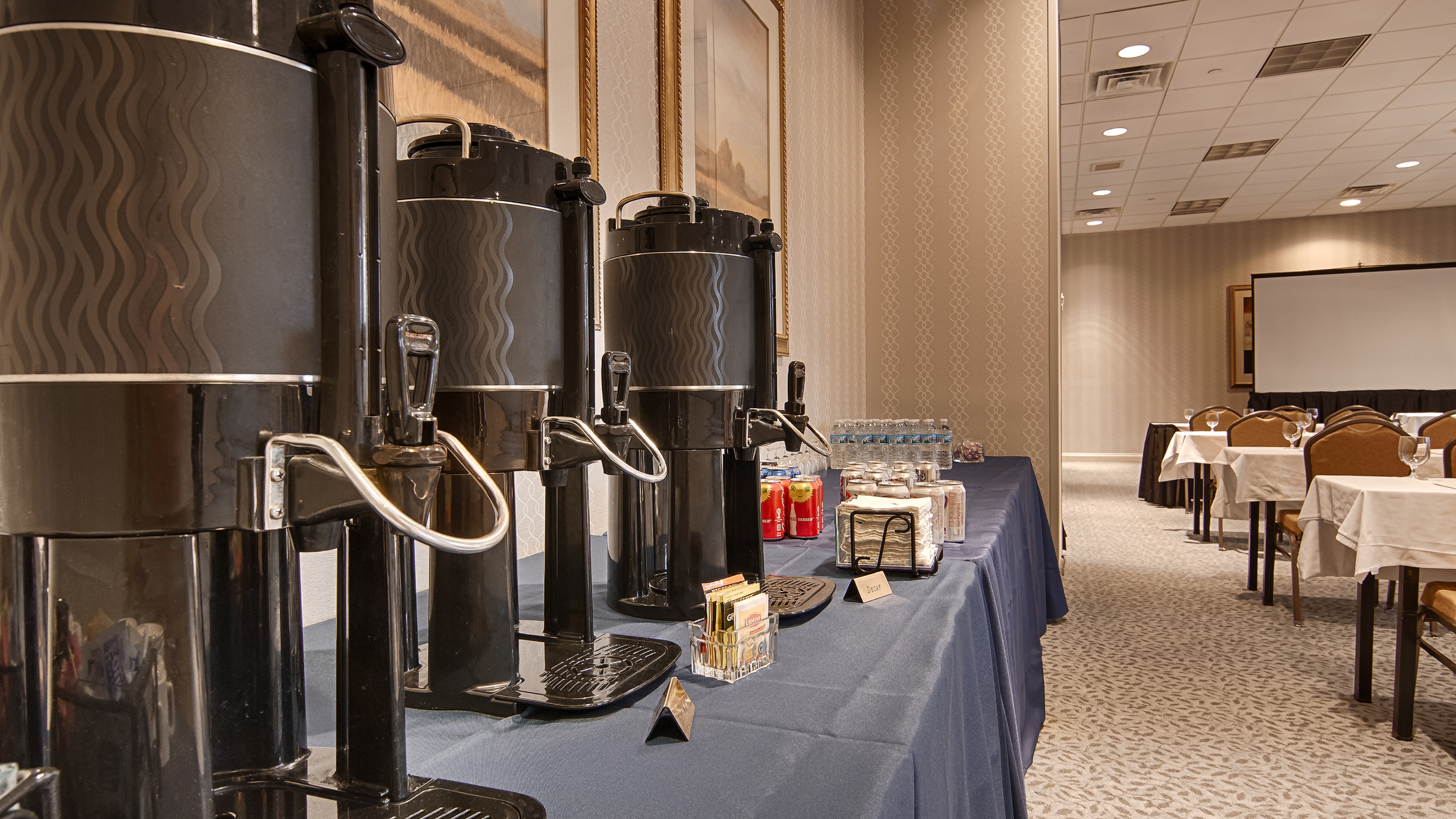 Event beverage station with coffee dispensers and soft drinks on blue table