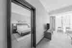 Bedroom with bed, bedside lamps and lounge area with chairs TV and rug