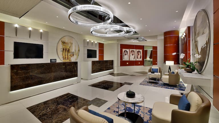 Lobby area with tables, chairs, sofas, paintings and TVs