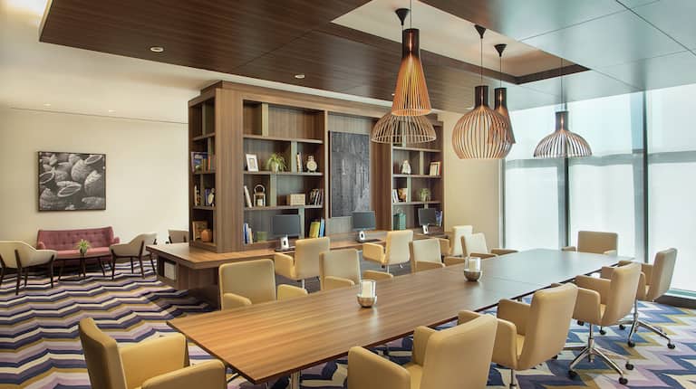 Common Working Area Long Table with Soft Seating Surrounding and Modern Lighting Overhead