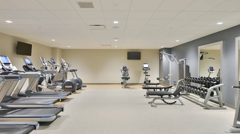 Fitness Center With Cardio Equipment, TVs, Weight Machine, Weight Benches, Free Weights, and Large Mirrors