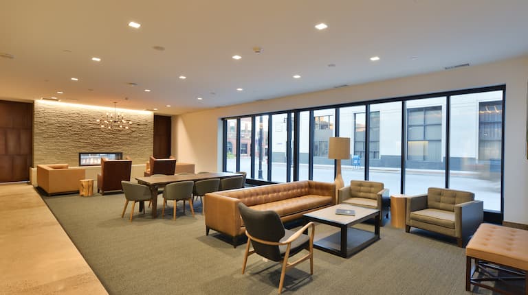 Soft Seating, Fireplace, Tables, and Lamp in Lobby Lounge Area With Large Windows
