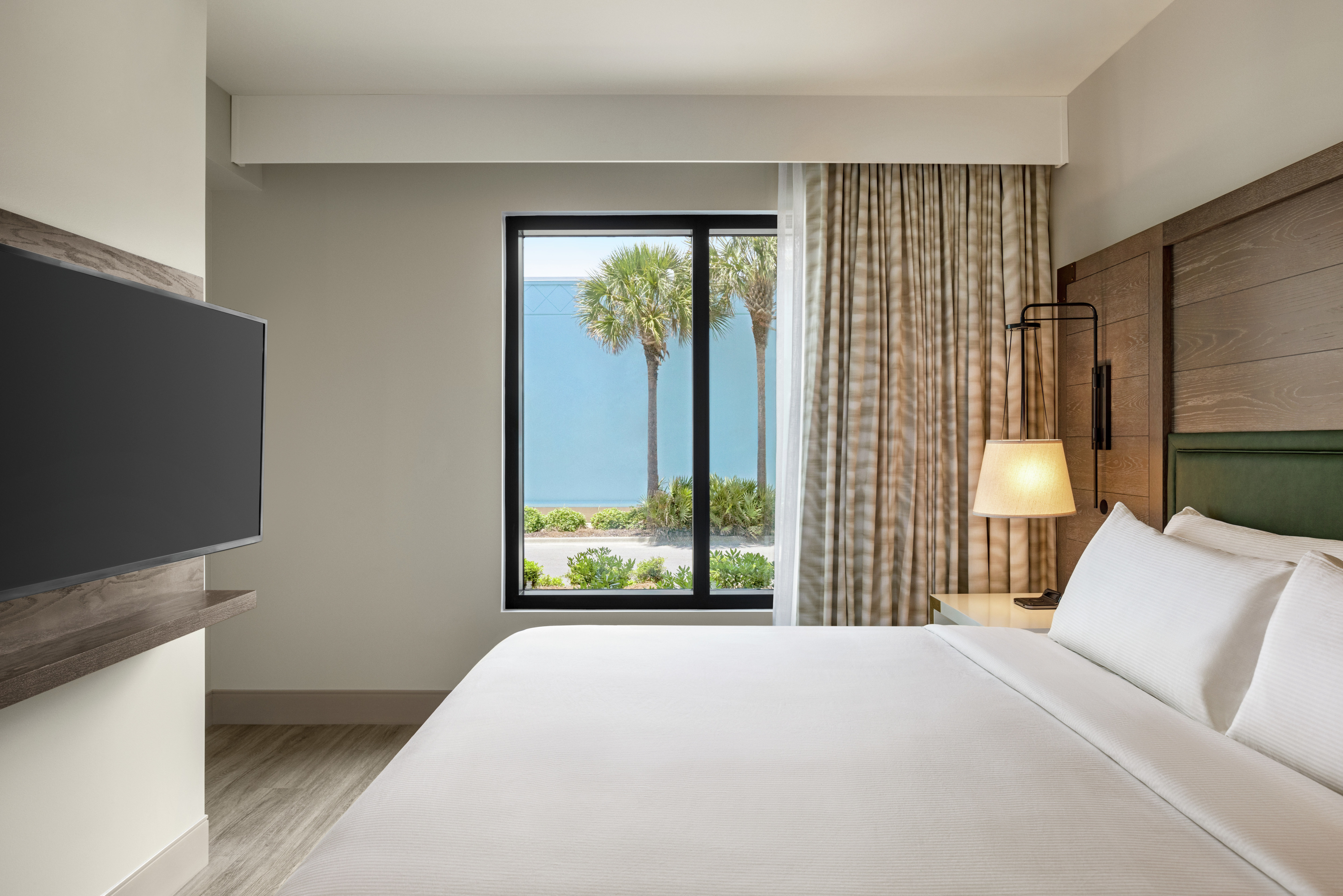 Comfortable guest bedroom with King bed, television and palm tree view