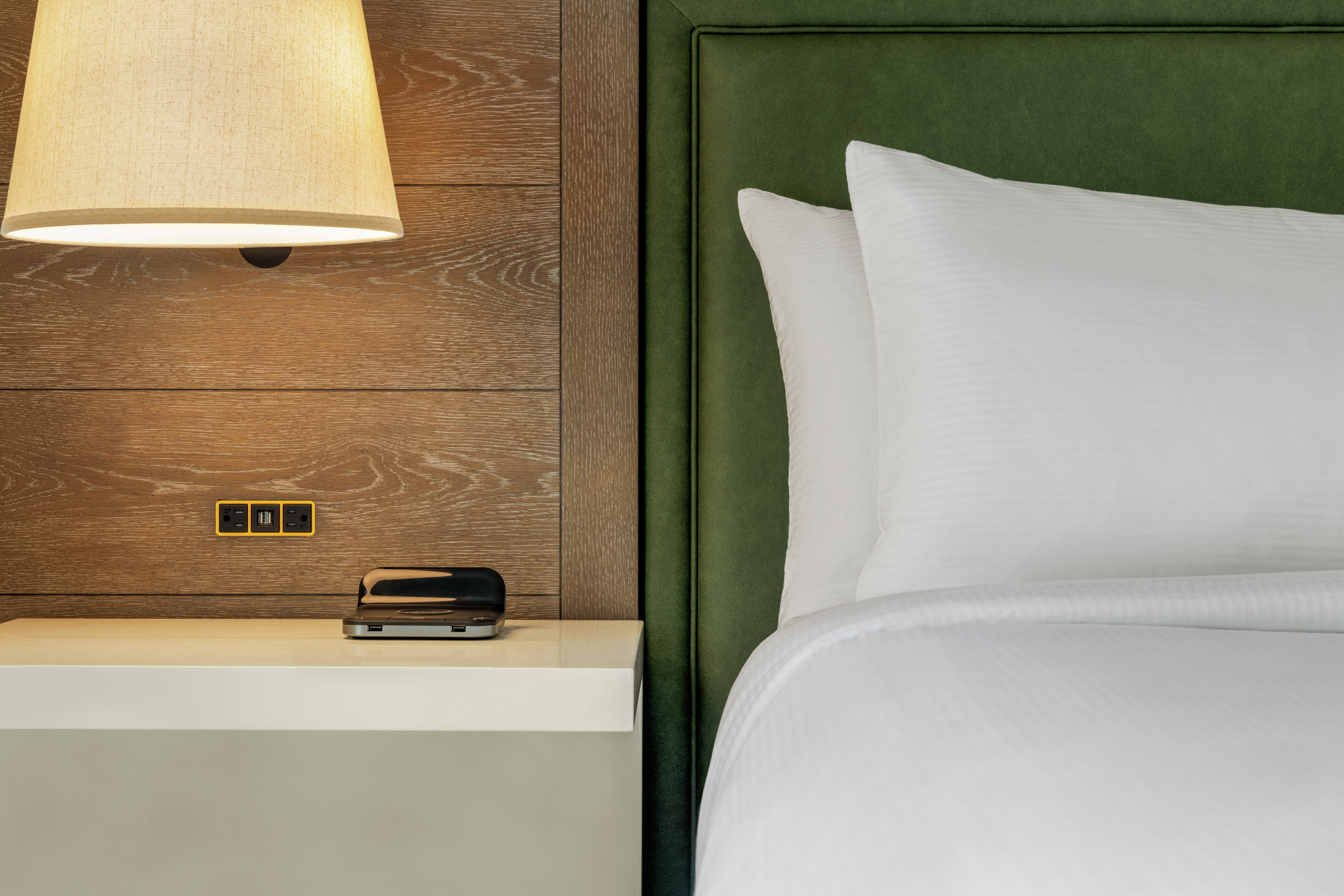 Close up of plush bedding and bedside table featuring USB ports and wireless phone charger