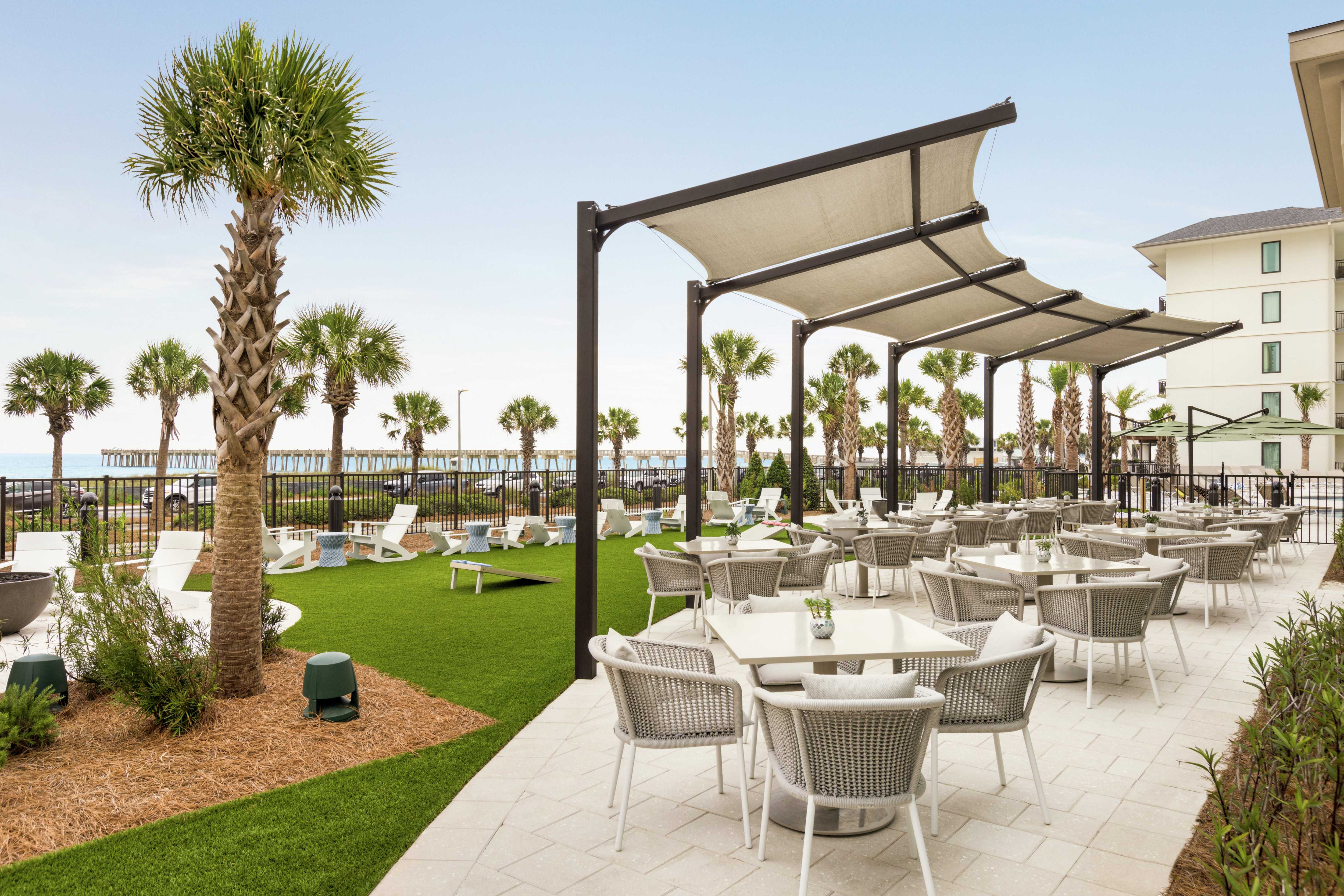 Expansive outdoor restaurant seating area featuring, fire pit, lush palm trees and ocean views