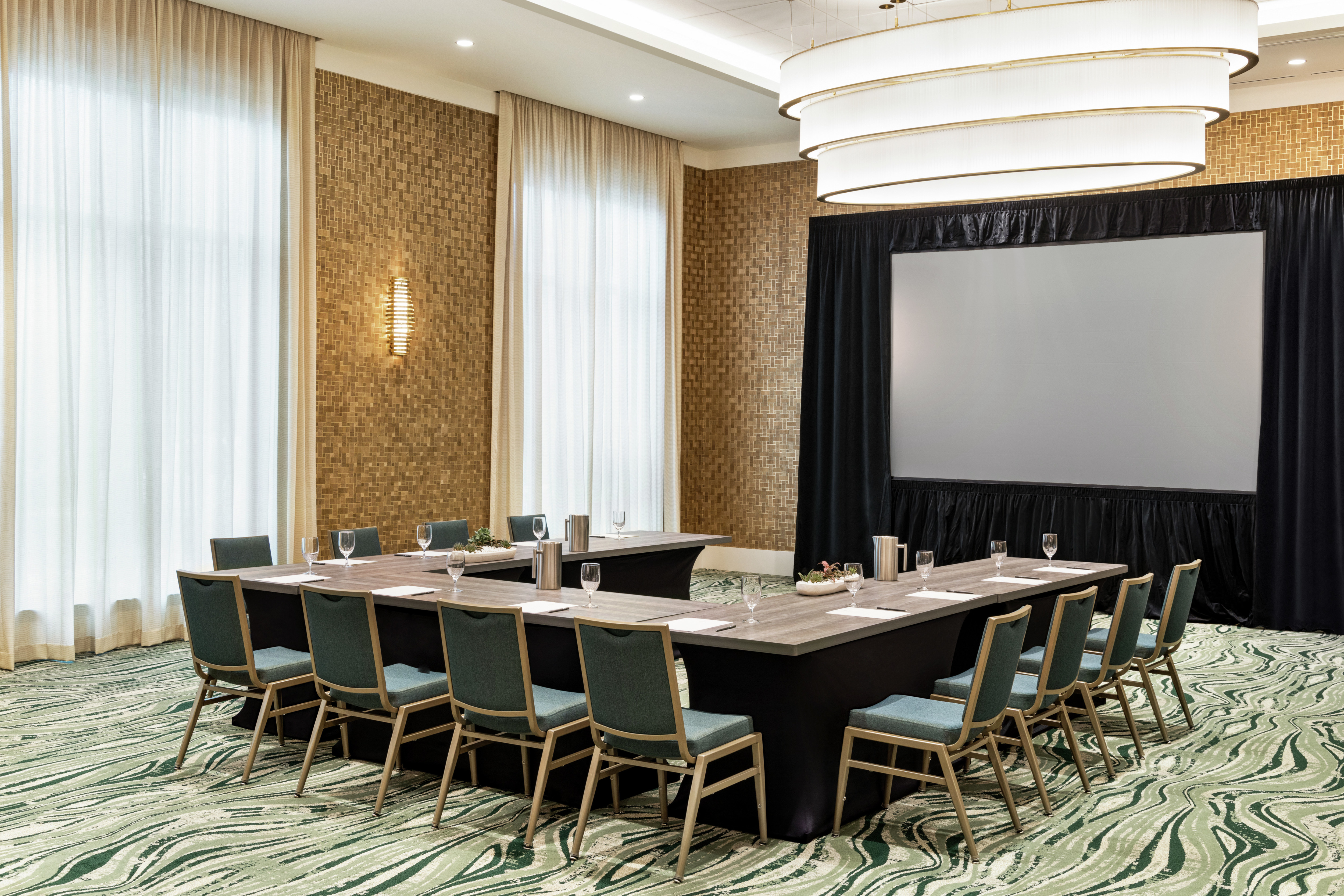 Spacious on-site meeting room featuring U-shape table setup and large projector screen at front of the room