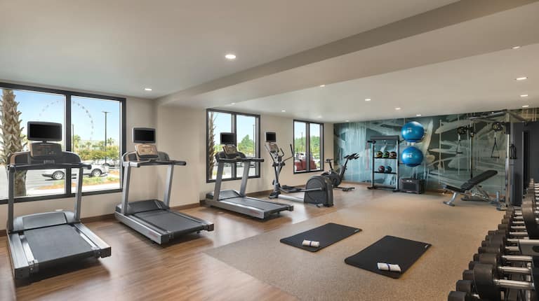 Spacious on-site fitness center featuring cardio machines, dumbbells and cable system