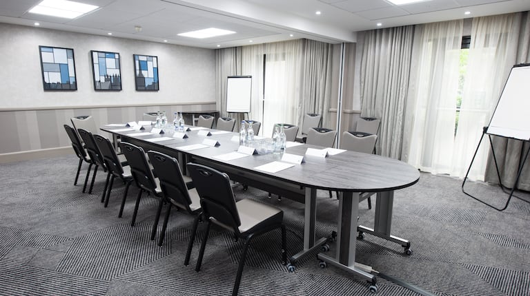 Boardroom With Seating for 14 Around Table, Wall Art, Two Presentation Easels, Two Speaker's Chairs and Window With Long Drapes