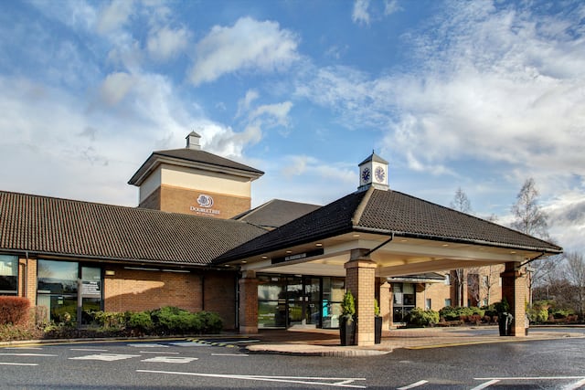 Daytime View of Hotel Exterior, Signage, Entrance, Landscaping, Porte Cochere, and Parking Lot