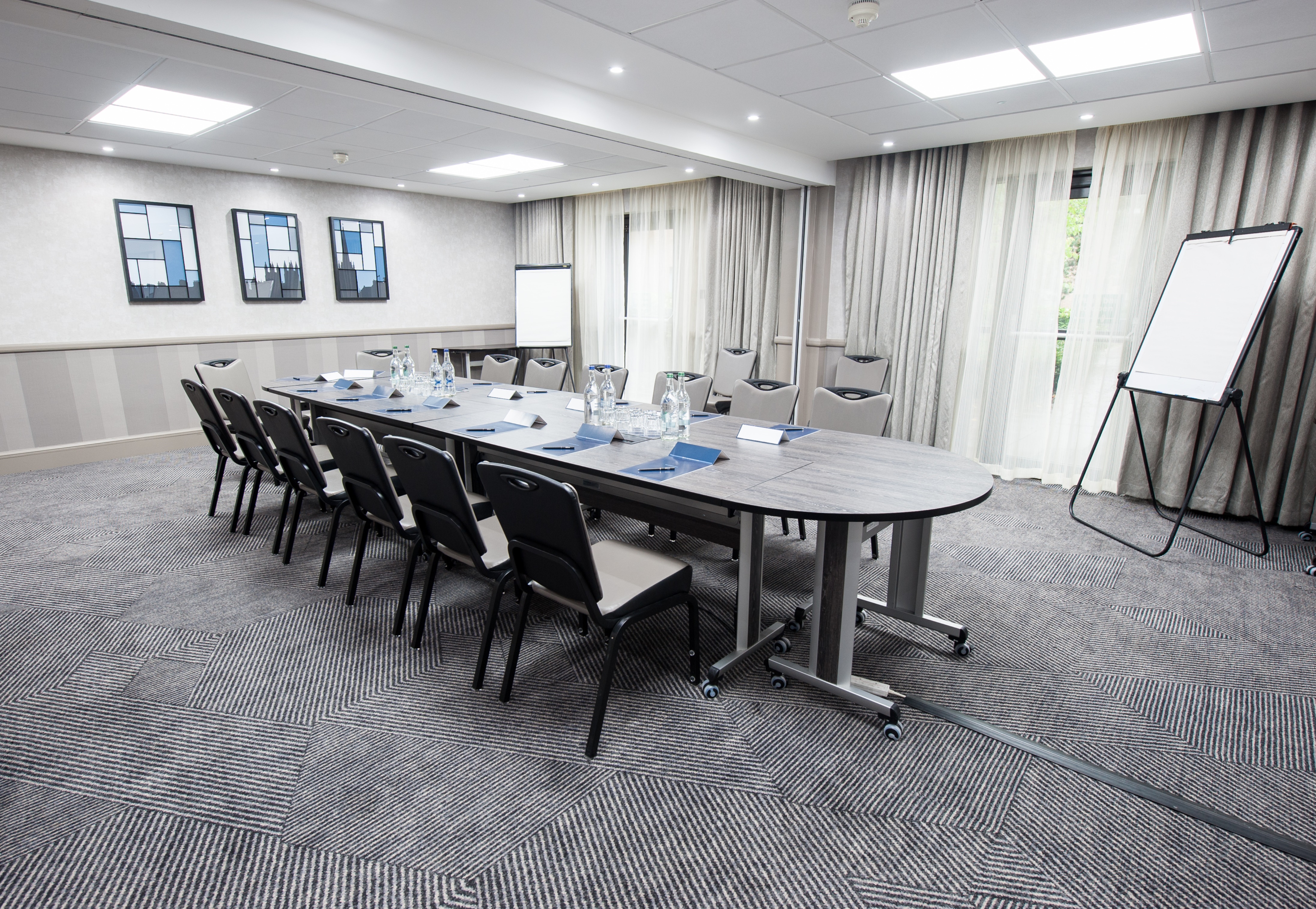 Boardroom With Seating for 14 Around Table, Wall Art, Two Presentation Easels, Two Speaker's Chairs and Window With Long Drapes